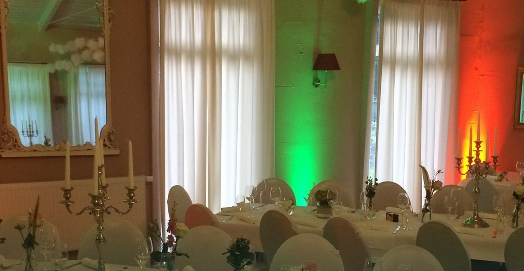 Festsaal mit gedeckten Tischen und farbiger Ambiente-Beleuchtung
